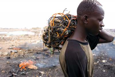 image: Ghanain man carrying electrical cables to reclaim wire