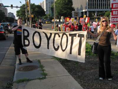 Two people holding banner which reads 'Boycott' with crowd behind