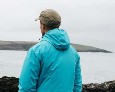 Back of person in turquoise outdoor rain jacket and cap