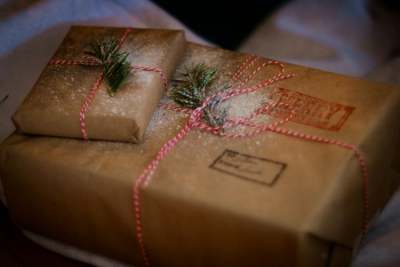 Two parcels wrapped in brown paper with winter evergreen twigs on them