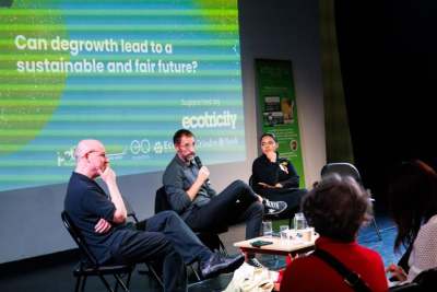 Three people sat infront of an audience in a panel discussion