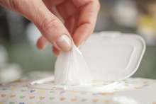 Person taking wet wipe from dispenser