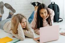 Two teenage girls looking at laptop and studying