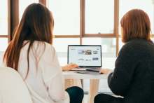 Backs of two people sitting looking at a laptop