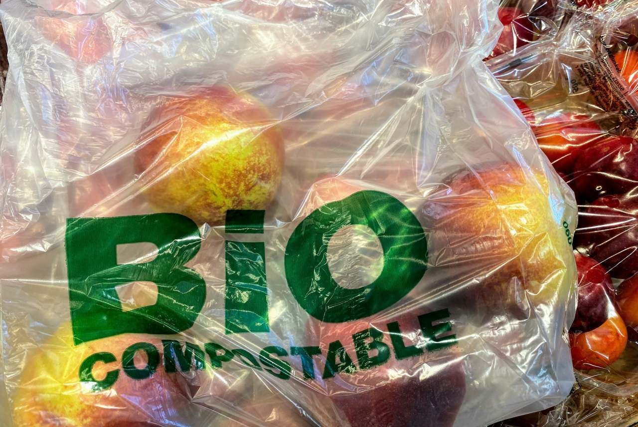 Plastic bag with apples inside. Bag writing says bio compostable.