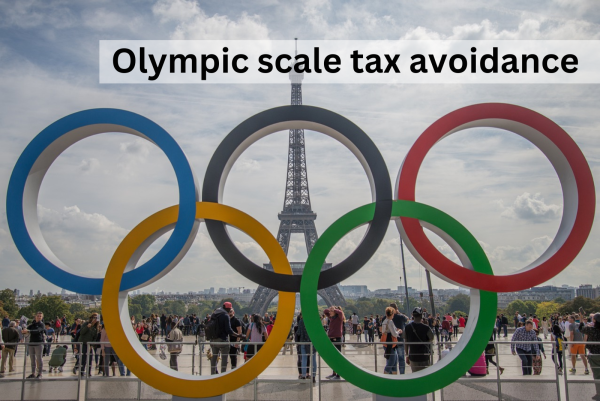 Public art of the 5 Olympic rings, situated in Paris with Eifel tower behind, and people in background