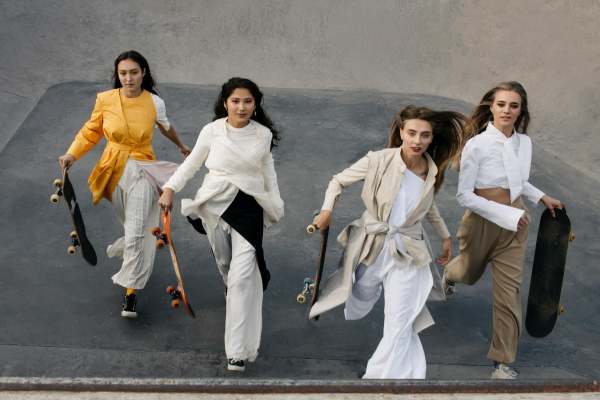 four women running holding skateboards